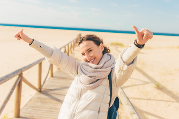 Young beautiful happy smiling woman making thumb up on the beach - ocean and sand background.