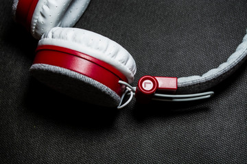 Poster - Big and white earphones for listening of music. Red plastic and skin. On a black background. Modern technologies. Portability.