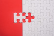 © mimiarifa - Incomplete white jigsaw puzzle pieces on red background