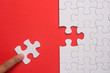 © mimiarifa - Close up of hand placing the last jigsaw puzzle piece on red background. Business and team work concept.