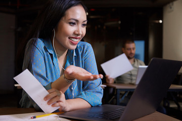 Portrait of cheerful Vietnamese businesswoman video calling colleague and talking about project development