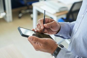 Wall Mural - Close-up image of businessman using stylus when working on smartphone