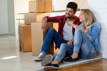 Wall Mural - Young happy couple moving in new home and unpacking boxes