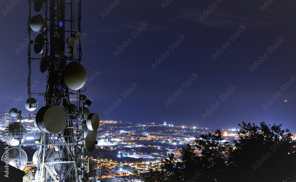 Telecommunications tower, antenna and satellite dish and city at night as background - obrazy, fototapety, plakaty 