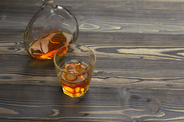 whiskey with ice cubes on wooden background