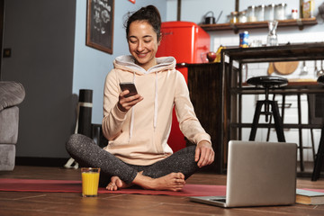 Poster - Happy healthy woman sitting on a fitness mat