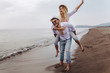 © Mediteraneo - Happy couple in love on beach summer vacations. Joyful girl piggybacking on young boyfriend having fun.
