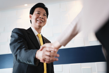 Handshake Between Happy Asian Manager And Hispanic Businesswoman In Office