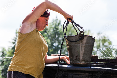 Fotomural A view of hardworking woman holding a bucket of metal container