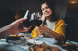 Romantic couple dating at night in restaurant, cozy atmosphere, beautiful young couple making cheers with glasses of red wine during romantic dinner, Sweet Couple Date Dinner