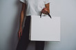 Young hipster girl wearing white t-shirt and holding blank white paper shopping bag, mock-up of white paper package, white background