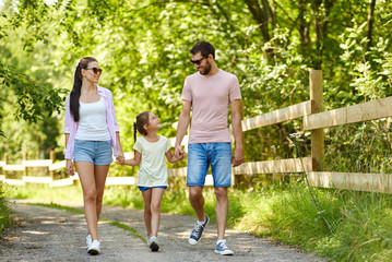 Wall Mural - family, leisure and people concept - happy mother, father and little daughter walking in summer park