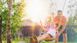 © Gorodenkoff - Joyous Father Pushes Swings with His Cute Little Daughter on Them. Happy Family Spends Time Together one Sunny Summer Day in the Idyllics Backyard.
