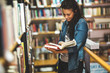 © BalanceFormCreative - Young female student read and learns by the book shelf at the library.Reading a book.