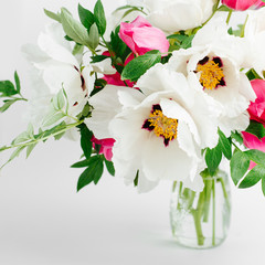 Wall Mural - Beautiful bouquet of white peonies and pink tulips in a glass vase on a white background