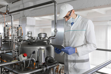 Wall Mural - Technologist stands with a tablet in the shop at the dairy Plant