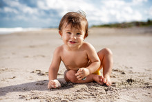 Happy Toddler Playing On The Beach On A Sunny Day