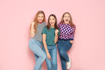 Wall Mural - Young women celebrating victory on color background