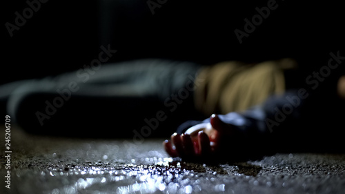 Fotografía Close-up bloody body of young woman lying on ground, terrible killing, robbery