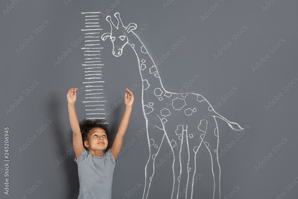 African-American child measuring height near chalk giraffe drawing on grey background - obrazy, fototapety, plakaty 