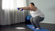 © motortion - Fat bachelor doing squats with dumbbells, working out at home, burning calories