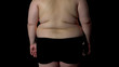 © motortion - Obese male on black background, excess weight problem, overeating, health care