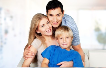 Canvas Print - Beautiful smiling family sitting at sofa on background