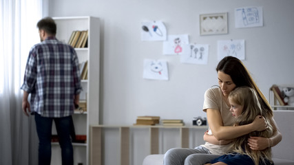 Wall Mural - Strict father angry after quarrel, scared wife and daughter embracing, abuser