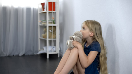 frightened girl with toy friend sitting on floor, scared of imaginary monster