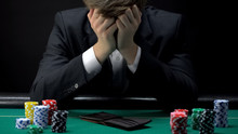 Young Devastated Businessman Losing Poker Game At Casino, Gambling Addiction