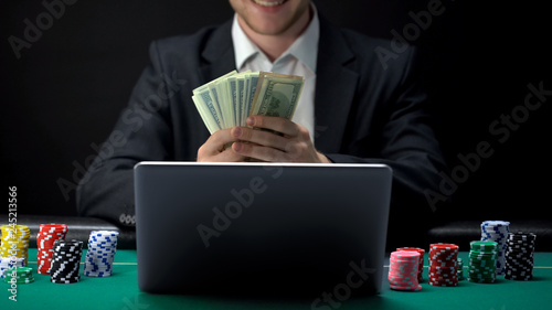 Fotografía Successful online casino player counting money in front of laptop, bet winner