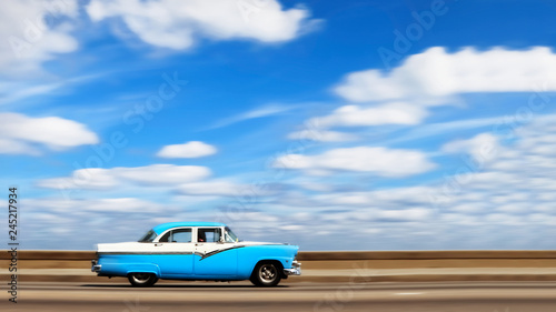Plakaty Kuba   amerykanski-jasny-niebieski-samochod-retro-nad-brzegiem-morza-w-stolicy-kuby-hawana-na-tle-blekitu