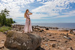 © Andzo Janovich - Young woman in long dress posing on rocks  on coast of sea, in hands holds a Viking sword