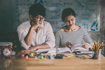Wall Mural - high school or college asian student group sitting at desk in class studying and reading, doing home