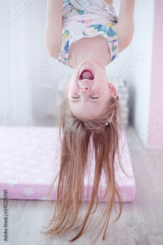 Fotomural baby girl hanging upside down and laughing