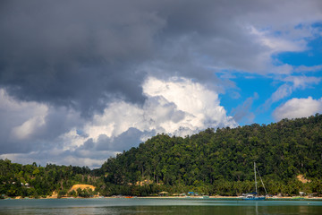 Tropical seaside landscape with sea water and greenery. Fishing boats and yacht in idyllic lagoon of tropical island.