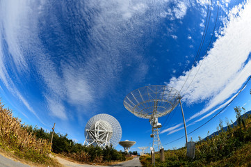 Array of satellite dishes or radio antennas against sky. Space o