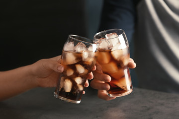 Wall Mural - Friends with glasses of tasty refreshing cola at table, closeup view