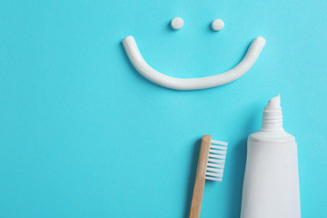 smiling face made of toothpaste, tube, brush and space for text on color background, top view