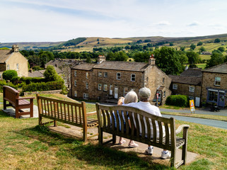 An elderly couple snuggling together on a bench, enjoying their retirement in the Yorkshire Dales