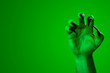Halloween, nightmare creature and evil monster horror story concept with a scary zombie or demon hand with creepy long black nails isolated on green with a clip path cutout and copy space