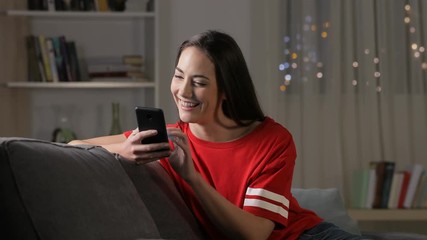 Poster - Happy teen using smart phone in the night sitting on a sofa at home