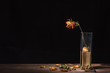 withered rose in glass vase, dry flower petals and leaves falling on table