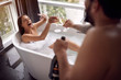 Happy couple have fun together in the bathtub and drinking champagne.