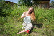 © papava - Red-haired girl sitting on the grass with a red cup of coffee on the background of camping in summer morning.