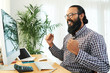 © DragonImages - Young cheerful bearded businessman expressing gladness while siting by desk in front of computer monitor