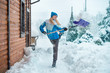 A woman cleans the snow in her yard in a country house.