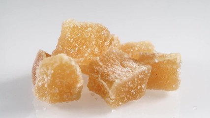 Wall Mural - Heap of crystallized candied ginger pieses rotating on white plate.  Yummy snack, better alternative to candy