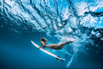 Wall Mural - Surfer woman with surfboard dive underwater with ocean wave.