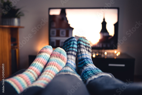 Fotomural Couple with socks and woolen stockings watching movies or series on tv in winter